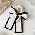 Detail van elegante zwart-witte strik-scrunchie met lange linten en satijnen textuur - Korte geknoopte witte strik