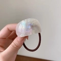 Macro shot of minimalist brown hair tie with a shimmering acetate hemisphere charm - Iridescent White
