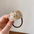 Detail of curved acetate hair tie featuring amber marble texture and brown elastic band - Beige Marbling