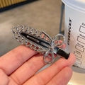 Dettaglio ravvicinato di un fermaglio per capelli a fiocco argento con inserto nero - Stile C-Clip in metallo con catena / Argento