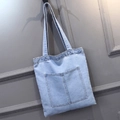Minimalist light blue denim tote bag with external pocket hanging on a wall - Style 1 Light Blue