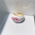 Detail of white enamel evil eye ring with pink eye design and gold plating on stone surface - White Pink