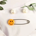 Variant of baby safety pin with orange smiley face design on a white marble background - Smiley Face Yellow
