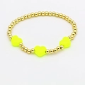 Gros plan d'un bracelet en perles dorées orné de trois cœurs en émail jaune néon - Jaune