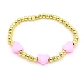 Detail of beaded bracelet with golden metal spheres and three pink resin heart charms - Pink