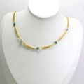 Vue détaillée du collier en chaîne dorée avec plusieurs perles œil bleu sur support blanc - Bleu