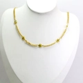 Détail d'un collier ras du cou doré avec perles œil grec jaunes sur buste blanc - Jaune