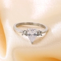 Detailaufnahme eines tropfenförmigen Zirkonia-Rings auf elegantem pfirsichfarbenem Seidenstoff - US 6 / Stahl mit klarem Hauptstein (KR111192-TOM)