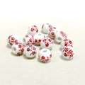 Primo piano di perle in ceramica da 10mm con motivi floreali rossi su porcellana - Piccolo Fiore di Prugno Rosso