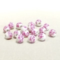 Dettaglio di perle in ceramica bianca da 10mm con motivi floreali viola su tessuto - Piccolo Fiore di Prugno Rosa Chiaro