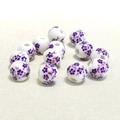 Vista macro di perle di ceramica bianca da 10mm con motivi floreali viola e fori passanti - Piccolo Fiore di Prugno Viola