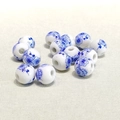 Macro shot of 10mm blue and white floral ceramic beads scattered on beige fabric - Blue and White Large Plum Blossom