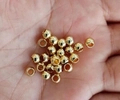 Nahaufnahme von goldenen Edelstahl-Hohlperlen für die Schmuckherstellung in der Hand - 2*1 mm Durchgangslochperle / Vergoldet