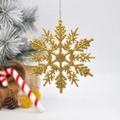 Sparkling gold glitter snowflake ornament hanging from a tree branch for holiday decor - Gold