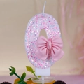 Macro detail of pink glitter number 0 birthday candle with a cute 3D bow decoration - Number 0