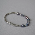 Dettaglio della fibbia irregolare in metallo argento e perle barocche scure iridescenti - Oro Bianco