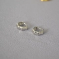 Dettaglio ravvicinato di orecchini a cerchio in argento a forma di bambù su tessuto grigio - Argento