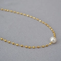 Elegant gold beaded necklace with a white pearl pendant on a soft grey background - Gold Plated + White Faux Pearl