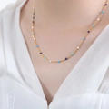 Golden titanium steel necklace with blue and white enamel beads worn on a model's neck - Necklace / Blue White