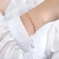 Minimalist red glazed bead bracelet in golden titanium steel on a woman's wrist - Bracelet / Red
