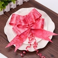 Detail view of a large red wedding bow with embossed rose patterns on a white decorative plate - Rose Print Red