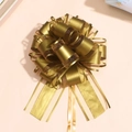 Detailed top view of a large golden metallic pull bow with multi-layered ribbon texture - Gold