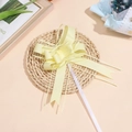 Close-up of pale yellow snow yarn bow ribbon on a woven mat for gift packaging decor - Yellow