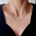 Detail of a thin gold chain necklace with small green enamel beads on a neck model - Green