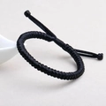 Macro shot of a black hand-woven bracelet with adjustable cord on a gray background - Vajra Knot / Black