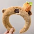 Detalle de diadema de oso marrón de peluche con decoración de caqui naranja en la oreja - Carpincho Durazno