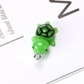 Detailed close-up of a green resin turtle pendant with realistic shell patterns and metal ring - Turtle