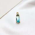 Detail of blue-green teardrop glass pendant with gold-plated claw setting on white silk - Light Blue