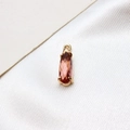 Macro view of water drop amber glass pendant with golden four-claw setting on white silk - Lotus Pink