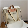 Khaki Canvas-Shopper mit braunen Ledergriffen und 'LIGHT FASHION' Print auf weißem Stuhl - Khaki