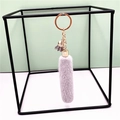 Close-up of light grey faux fox fur tassel keychain hanging on a metal display stand - Gray