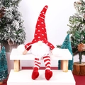 Dettaglio di uno gnomo di Natale con cappello rosso a maglia e gambe a strisce sulla neve - Gnomo a gambe lunghe luminoso Rosso