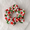 Detailed top view of a white satin Christmas scrunchie with holly and red ball prints - Style 4 (White Holly Red Ball)