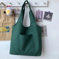 Minimalist green canvas tote bag with outer pocket hanging on a wall hook - Green