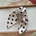 Detailopname van elegante witte haarklem met stippen en French Paris-label op lint - Grote stippen / Beige
