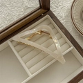 Vista de detalle de pinza de pelo triangular blanca nacarada en joyero de madera elegante - Color Sirena Nacarado