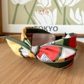 Macro detail of color-block geometric pattern satin headband with a twisted knot design - Bow Headband / Green Patchwork
