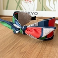 Detail of colorful geometric pattern knot headband on a rustic wooden tray with art poster - Bow Headband / Color Block Red Green