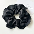 Vista dettagliata dell'elastico in raso nero a pieghe con bordi arricciati e consistenza setosa - Scrunchie con Volant Nero