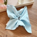 Macro detail of a light blue silk scrunchie scarf with a smooth satin texture on wood - Lake Blue