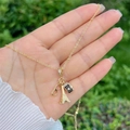 Detail van gouden hanger ketting met Eiffeltoren, bril en camera hangers in de hand - Eiffeltoren