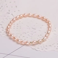 Detail of natural oval pink pearls bracelet with golden beads on white lace background - Adjustable Open / Pink