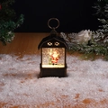 Christmas lantern with Santa Claus figurine and swirling glitter in bronze barn frame - Antique Gold Santa Claus with Backpack