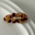 Macro shot of wavy acetate hair clip with tortoiseshell pattern on white ceramic plate - Tortoiseshell