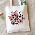 Chic Halloween tote bag with Bad Witch Vibes print in a sunny outdoor beach setting - Bad Witch Vibes