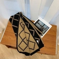 Klassischer Strickschal mit Karomuster in Schwarz und Khaki auf einem Holztisch - Kamel & Schwarz Argyle